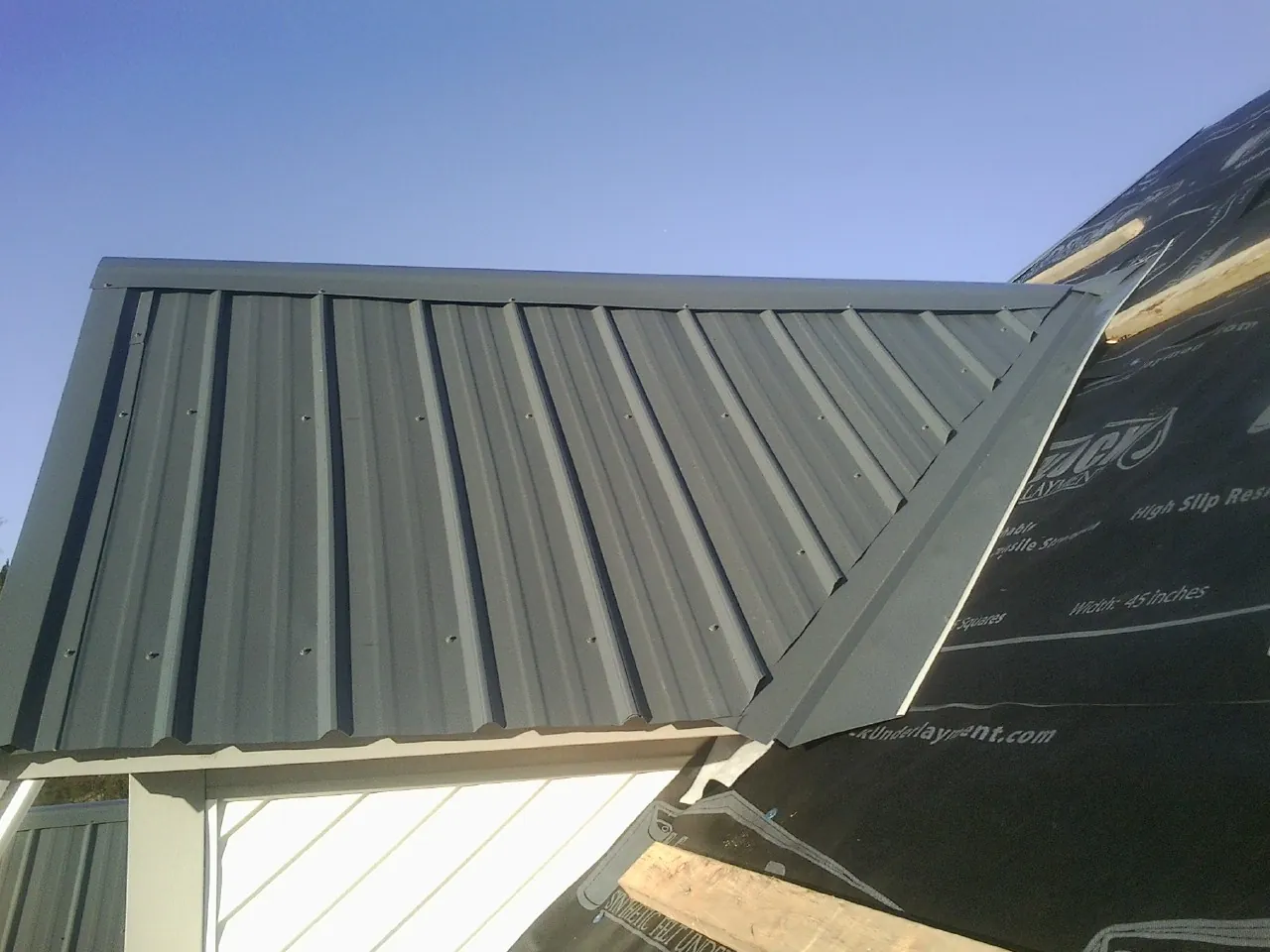Gray metal roof panels going on over a garage gable in Galva