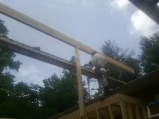 Carpenter setting a ridge beam over a new addition frame — Ice Dam Removal by Roofing Brothers in Galva