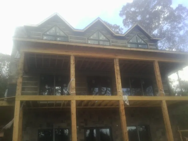 Dormers and porch framing on a large log home under construction — Roof Coating work by our crew in Galva