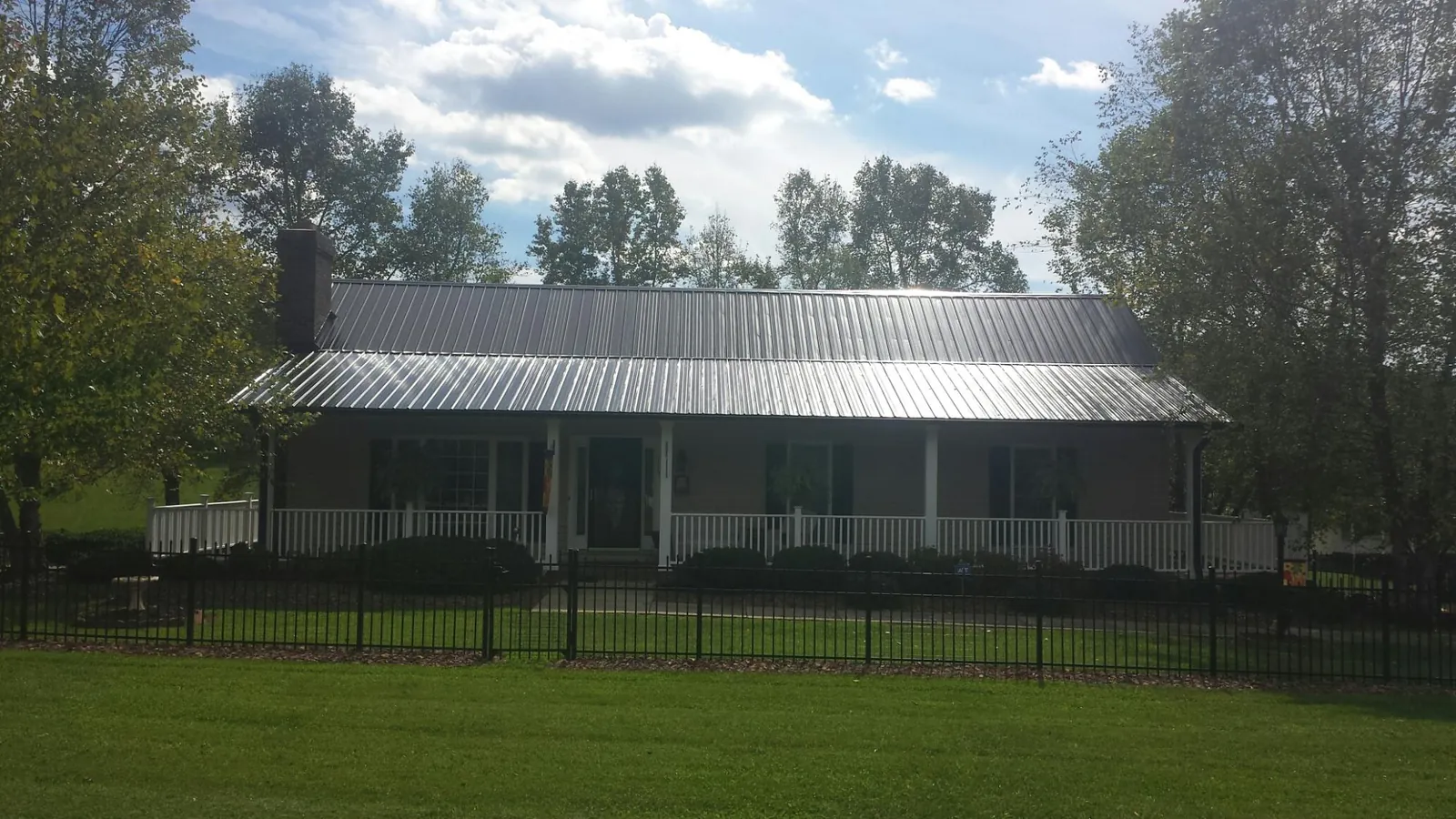 Gray metal roof on a brick ranch with a full width front porch — Gutter Guard Installation work by our crew in Galva