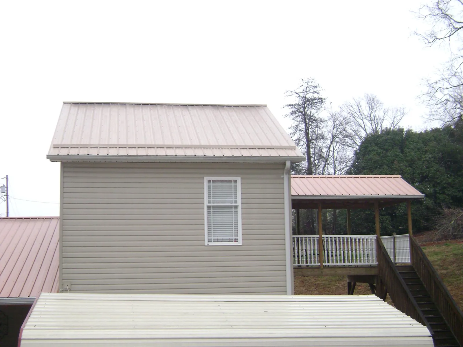 Tan metal roofs on a two story addition and attached porch, from a Roof Replacement job in Galva