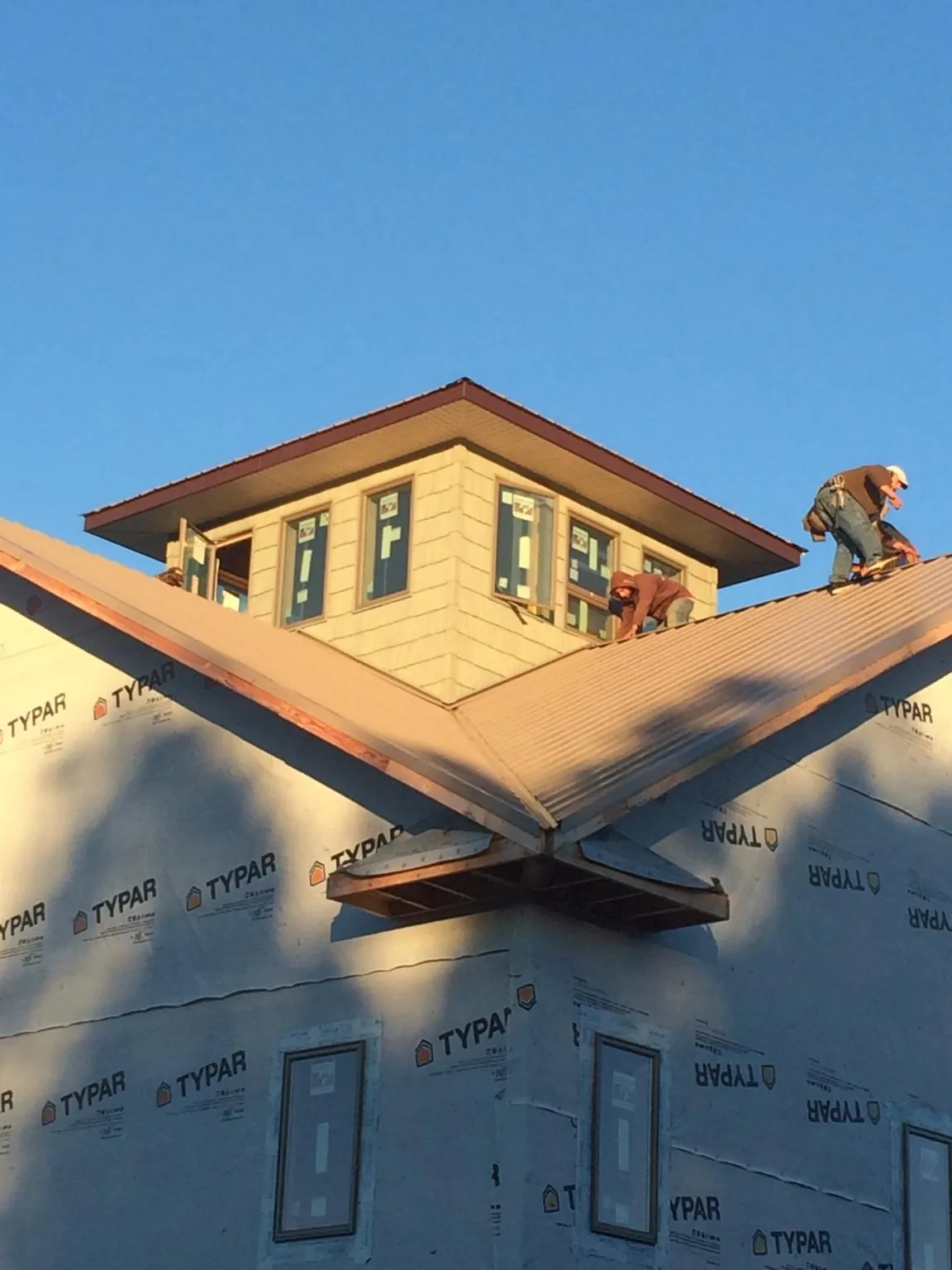 Roofers working around a rooftop cupola on a new metal roof at sunset — Roof Waterproofing in Galva by Roofing Brothers